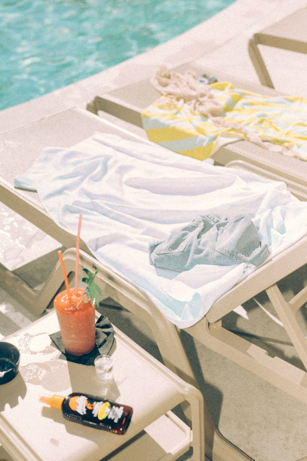 Sunbed with towel, sunglasses, and a tropical drink by the pool at Marina Resort Benidorm, evoking summer relaxation.