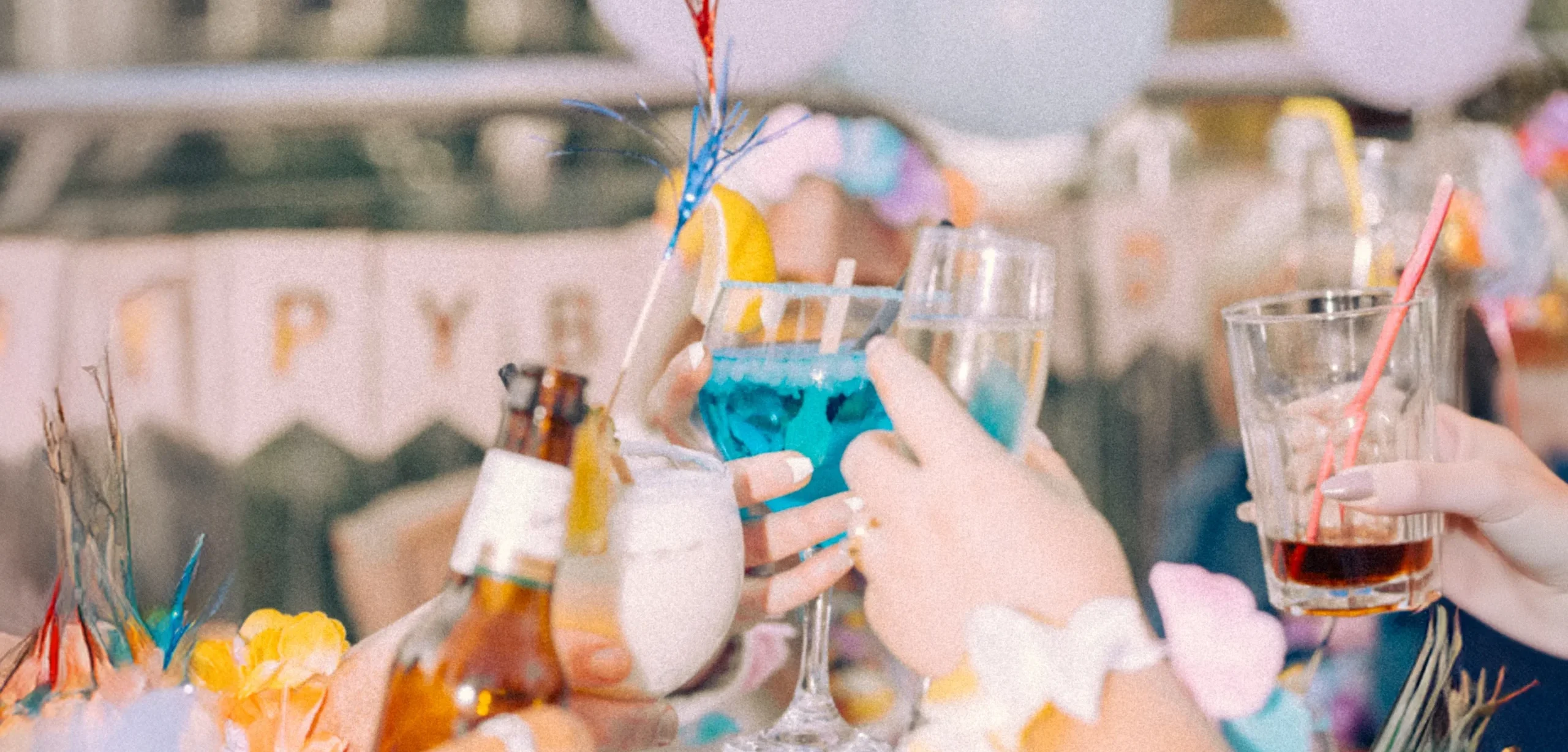 Close-up of colorful cocktails and drinks being raised in a toast during a lively party celebration